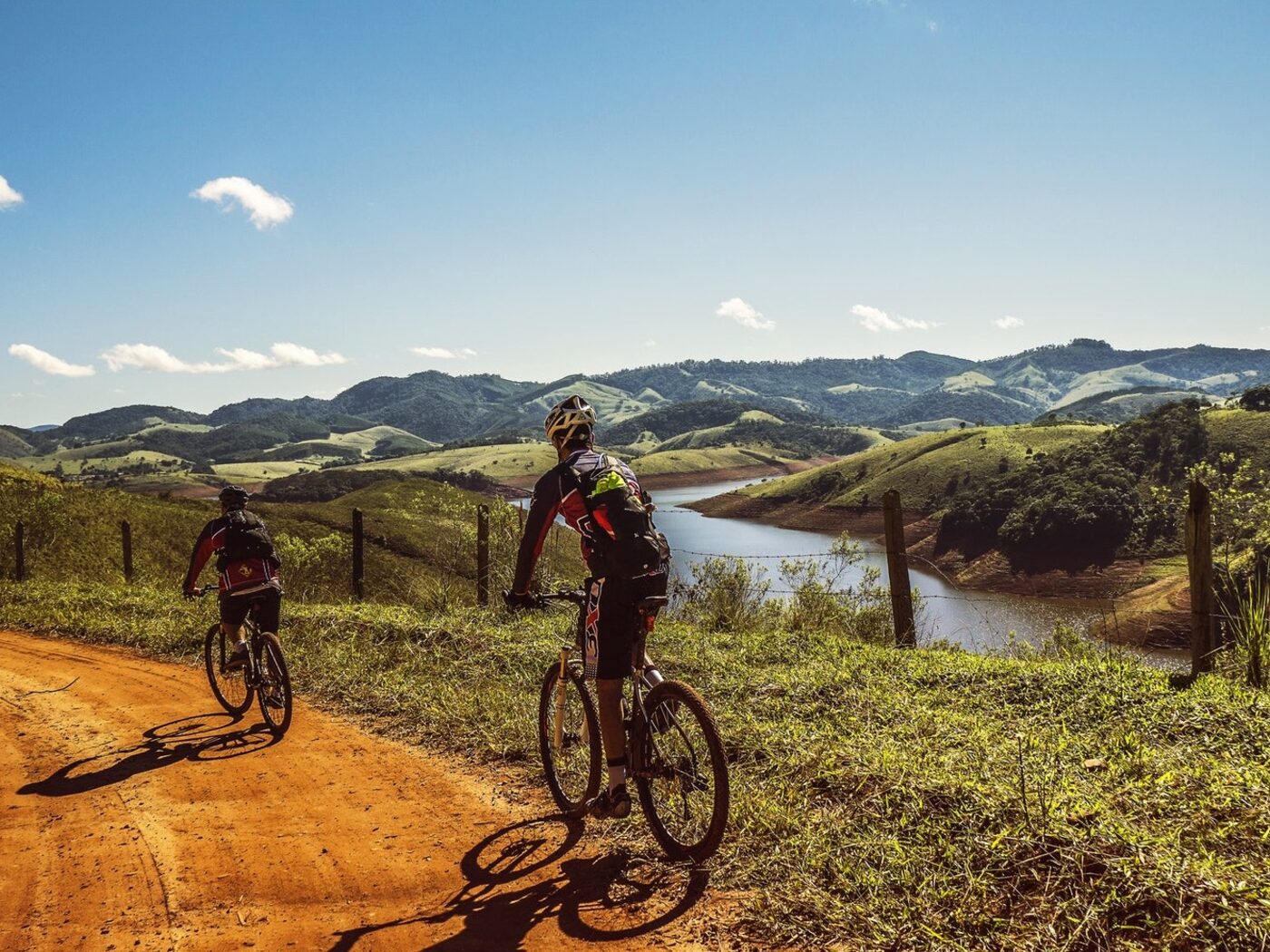 Two mountain bikers exploring a scenic trail beside rolling hills and water